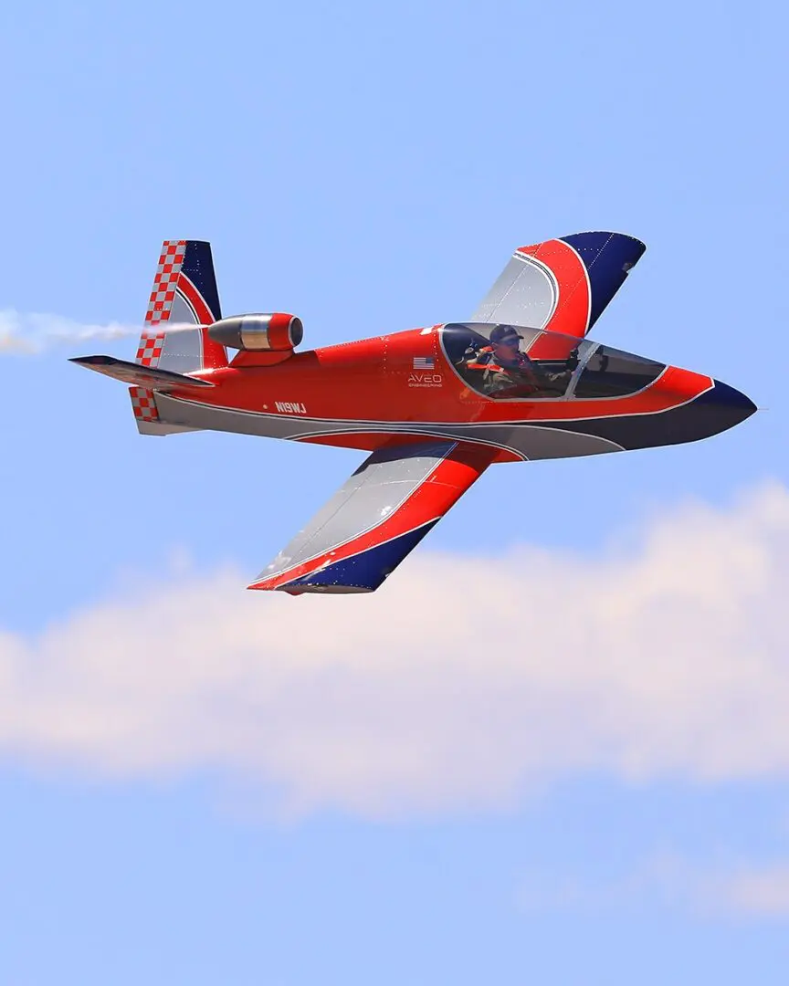 A red and blue plane flying in the sky.