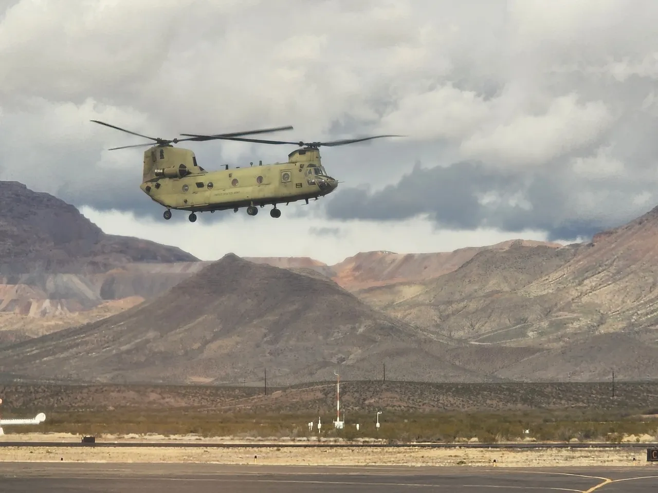 A helicopter flying over the mountains in front of some power lines.