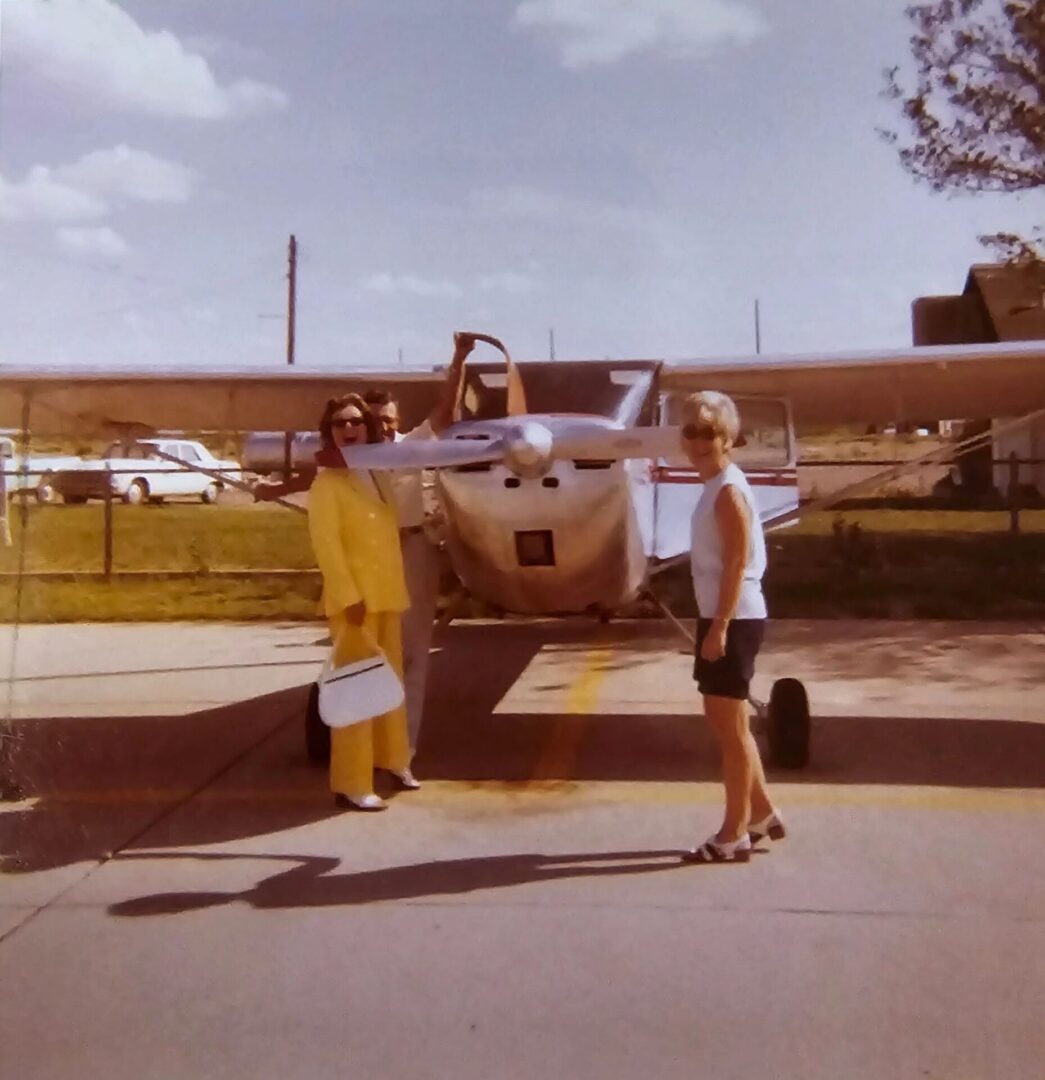 A couple of people standing next to an airplane.