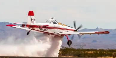 A red and white plane is flying over the ground