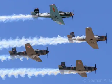 Four planes flying in formation with smoke coming out of the back.