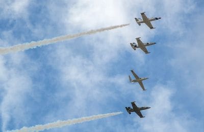 Four planes flying in formation with smoke trailing behind them.