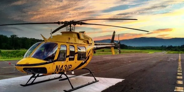 A yellow helicopter sitting on top of an airport runway.