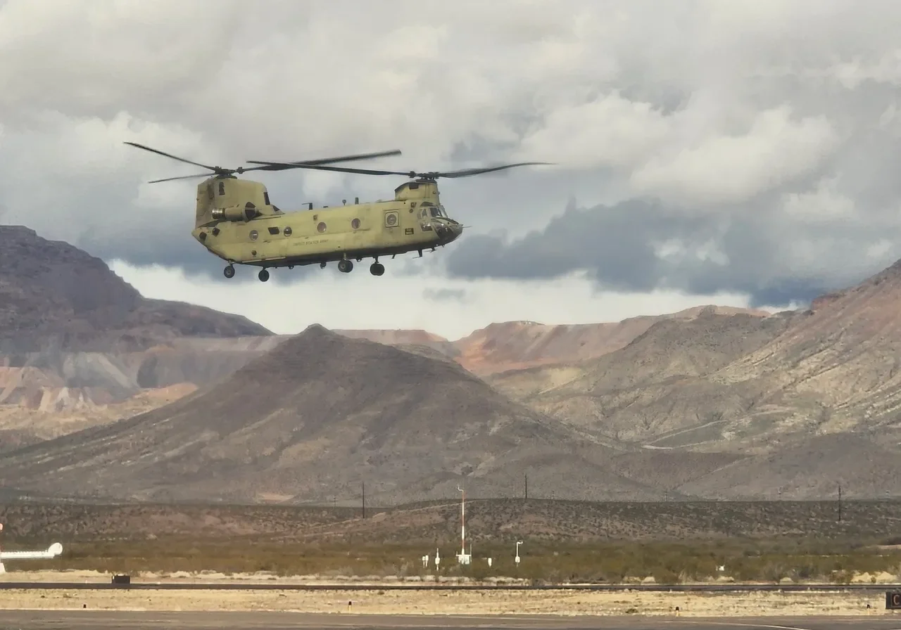 A helicopter flying over the mountains in front of some power lines.